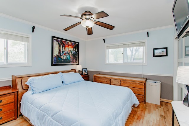 bedroom featuring light wood-type flooring, ornamental molding, and a ceiling fan