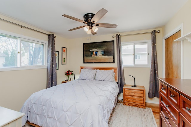 bedroom featuring baseboards, multiple windows, a ceiling fan, and wood finished floors