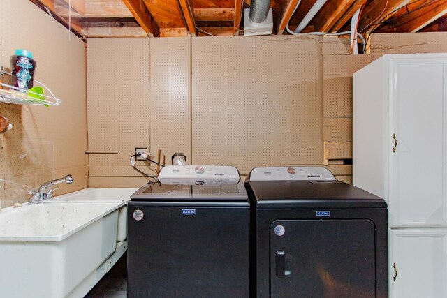 laundry area featuring cabinet space, separate washer and dryer, and a sink