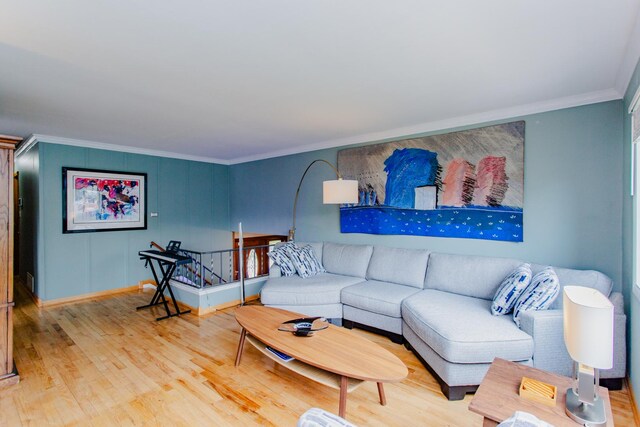 living room featuring baseboards, ornamental molding, and light wood-type flooring