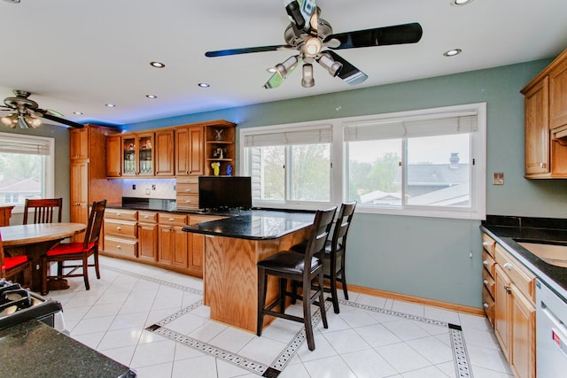 kitchen with dishwashing machine, ceiling fan, light tile patterned floors, and brown cabinets