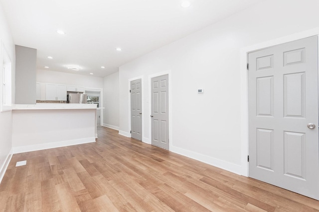unfurnished living room featuring recessed lighting, light wood-style floors, and baseboards