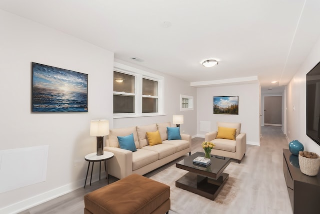 living area featuring light wood-style flooring, visible vents, and baseboards