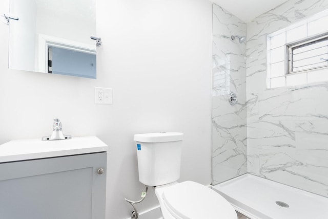 bathroom with toilet, vanity, and a marble finish shower