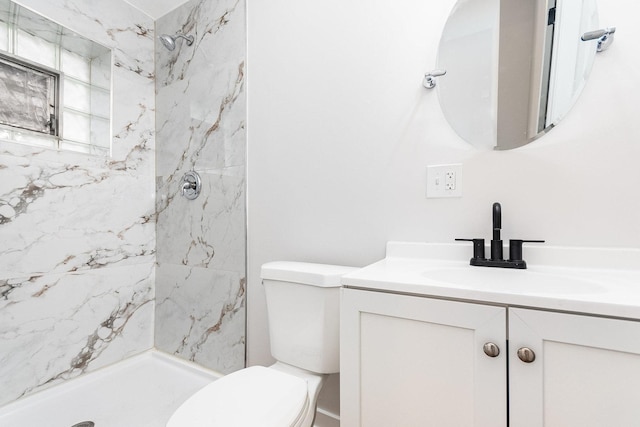 bathroom featuring toilet, vanity, and a marble finish shower