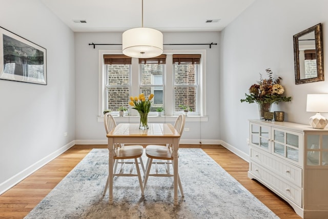 dining space featuring baseboards, light wood-type flooring, and visible vents