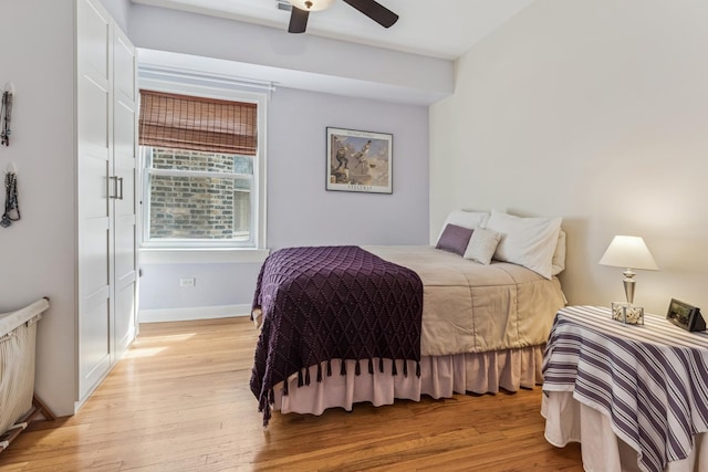 bedroom featuring a ceiling fan, baseboards, and light wood finished floors