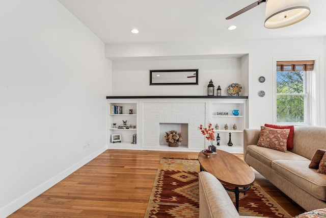 living room with a ceiling fan, a fireplace, wood finished floors, baseboards, and recessed lighting