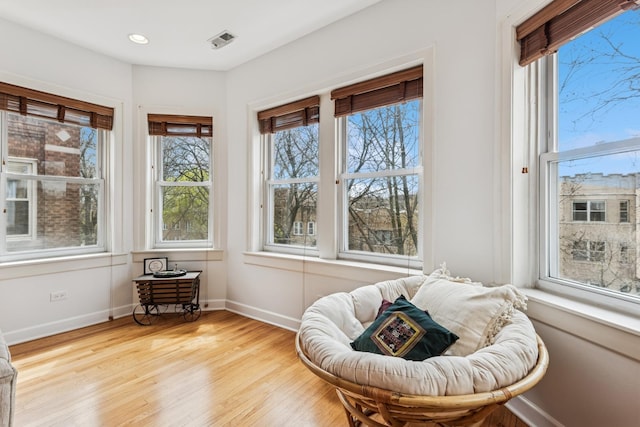 sitting room with baseboards, visible vents, a wealth of natural light, and wood finished floors