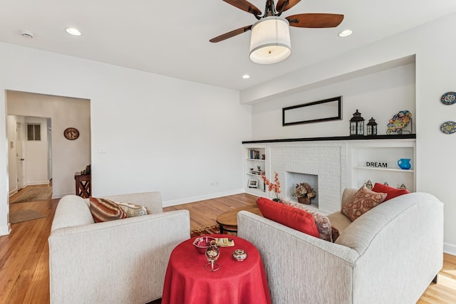 living area with a ceiling fan, a fireplace, baseboards, recessed lighting, and light wood-style flooring
