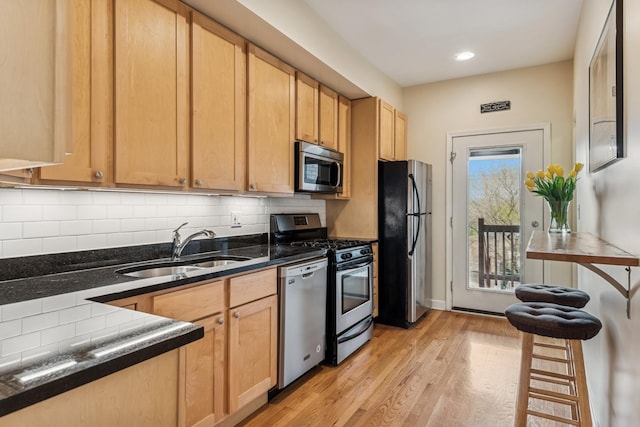 kitchen featuring light wood-type flooring, recessed lighting, a sink, backsplash, and stainless steel appliances