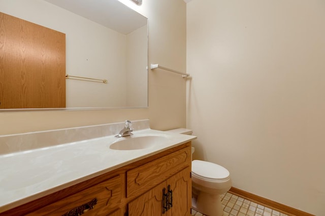 bathroom with baseboards, toilet, and vanity