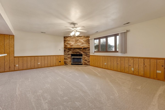 unfurnished living room with wood walls, ceiling fan, and wainscoting