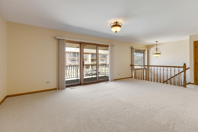 spare room with carpet floors, visible vents, and baseboards