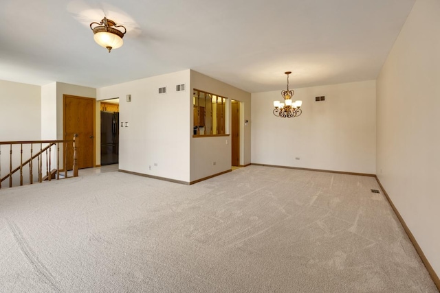 empty room featuring baseboards, visible vents, light colored carpet, and an inviting chandelier