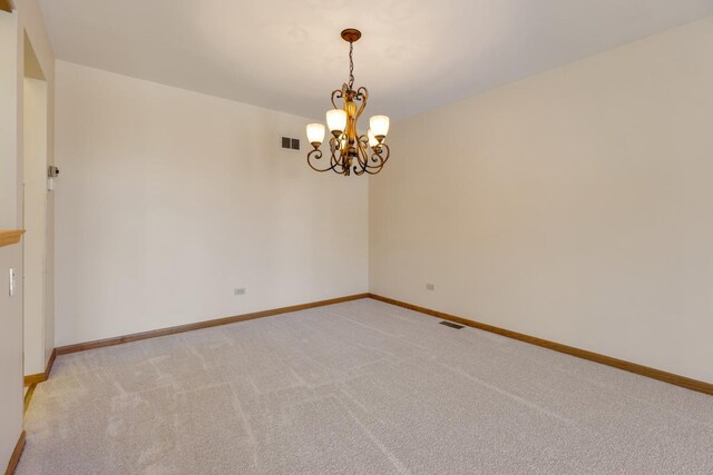 spare room featuring baseboards, visible vents, an inviting chandelier, and light colored carpet