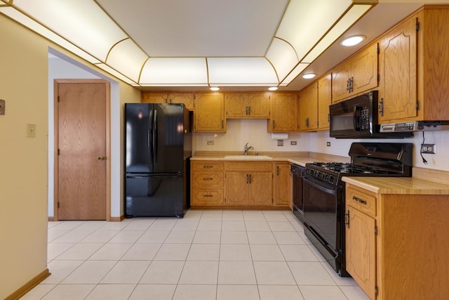 kitchen featuring brown cabinetry, black appliances, a sink, and light countertops