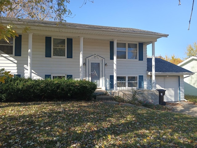 bi-level home with a garage, a shingled roof, concrete driveway, and covered porch