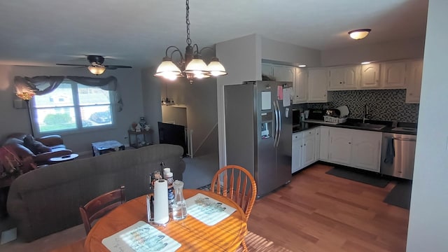 kitchen featuring dark countertops, a sink, light wood finished floors, white cabinetry, and appliances with stainless steel finishes