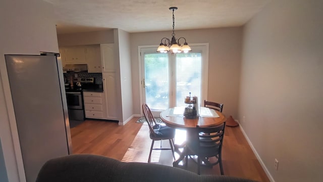 dining room featuring a chandelier, light wood-type flooring, and baseboards