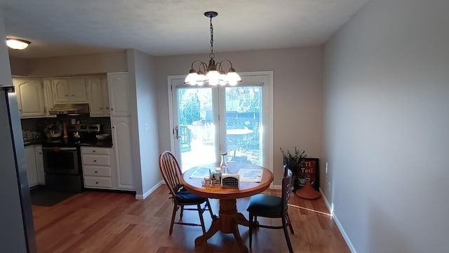 dining area with a chandelier, light wood finished floors, and baseboards
