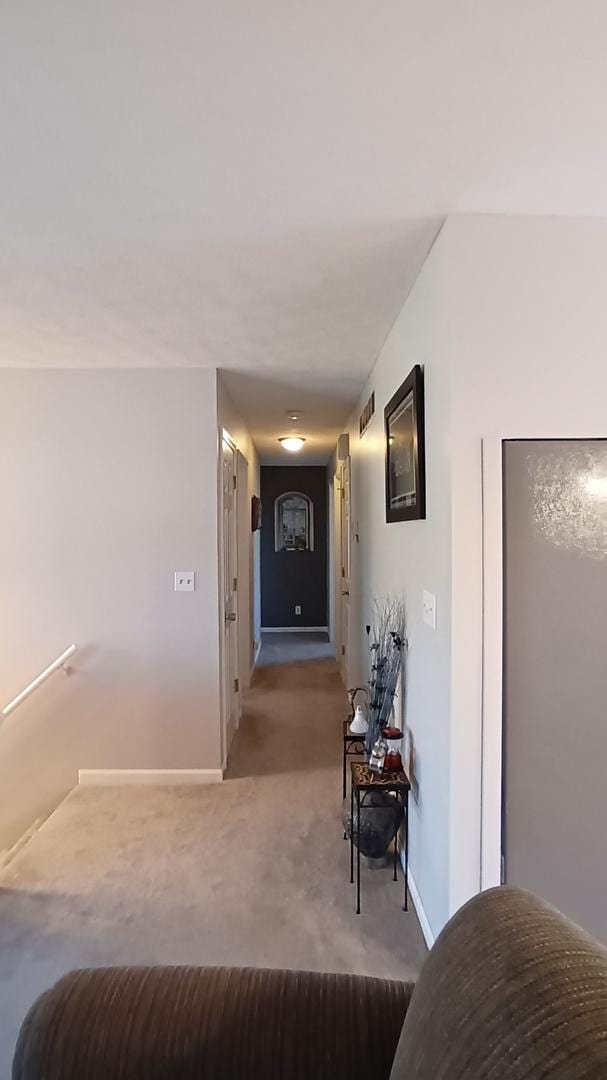 hall with baseboards, visible vents, and carpet