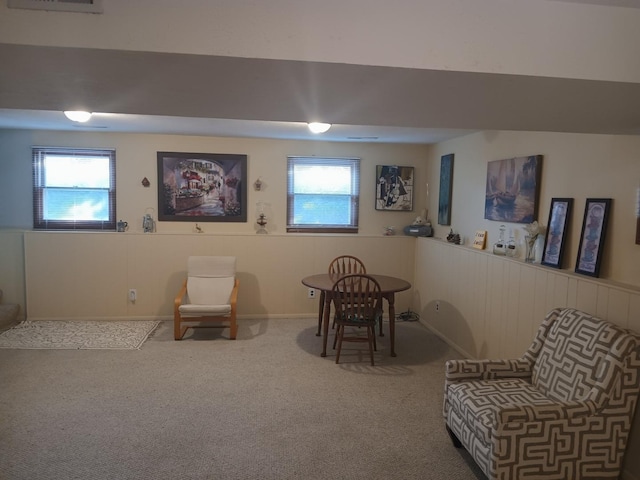 living area featuring a wainscoted wall, visible vents, carpet, and a healthy amount of sunlight