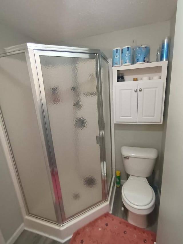 bathroom with a shower stall, toilet, and baseboards