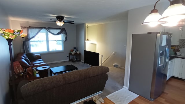 living area featuring wood finished floors, baseboards, and ceiling fan