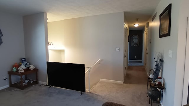 hallway featuring carpet, visible vents, baseboards, and an upstairs landing