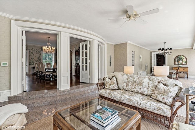 living room featuring brick wall, ornamental molding, granite finish floor, and ceiling fan with notable chandelier