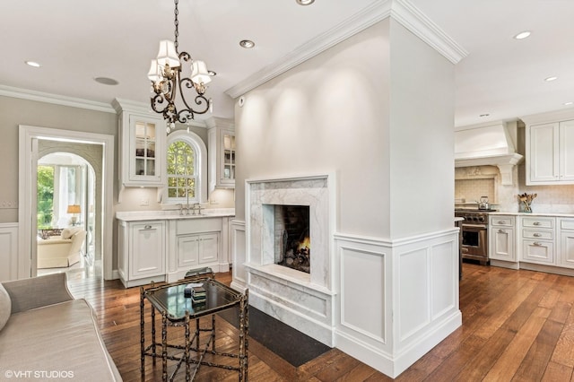living room with dark wood finished floors, recessed lighting, a notable chandelier, a premium fireplace, and crown molding