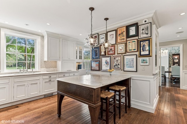 kitchen with a sink, hardwood / wood-style floors, an inviting chandelier, light countertops, and ornamental molding
