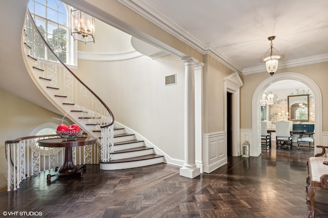 foyer with visible vents, stairs, ornamental molding, and an inviting chandelier