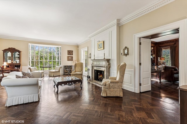 living area featuring a fireplace, a decorative wall, a wealth of natural light, and ornamental molding