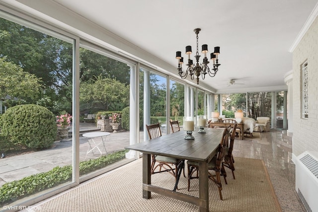sunroom / solarium featuring outdoor dining area, plenty of natural light, and ceiling fan with notable chandelier