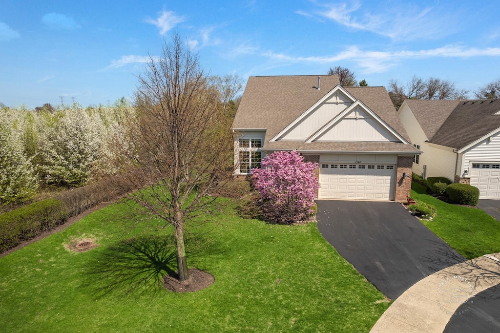 1544 Mansfield Dr, Aurora, IL 60502 - view of front of house with board and batten siding, brick siding, driveway, a front lawn, and an attached garage