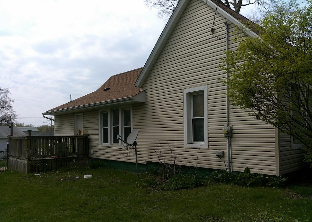 701 S Cain St, Clinton, IL 61727 - view of property exterior featuring a shingled roof, a yard, and a deck
