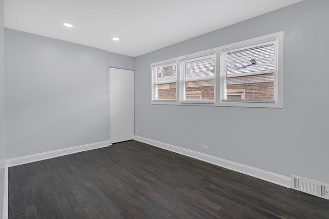 empty room featuring dark wood-style floors, baseboards, visible vents, and recessed lighting