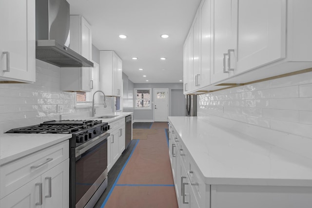 kitchen with a sink, tasteful backsplash, appliances with stainless steel finishes, and wall chimney range hood
