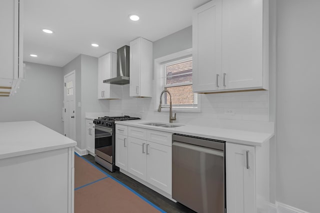 kitchen featuring stainless steel appliances, light countertops, a sink, wall chimney exhaust hood, and tasteful backsplash