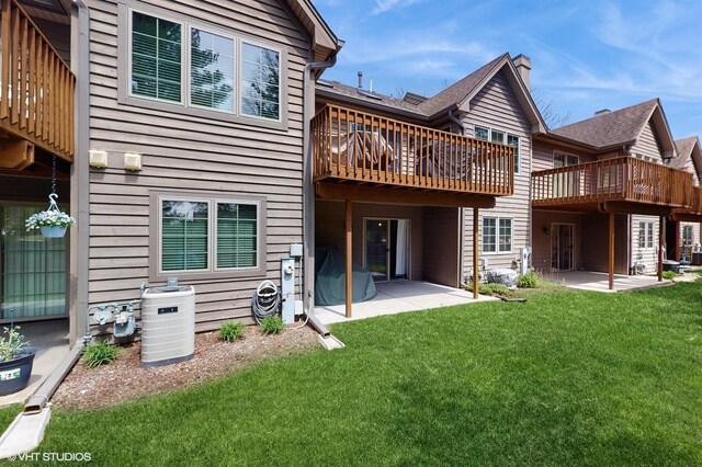 back of property featuring a wooden deck, a patio, and a yard
