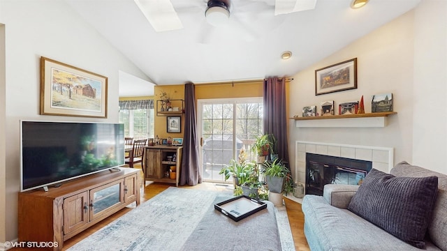 living area featuring ceiling fan, a fireplace, wood finished floors, and lofted ceiling