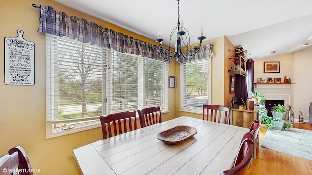 dining area featuring wood finished floors, a chandelier, and a fireplace