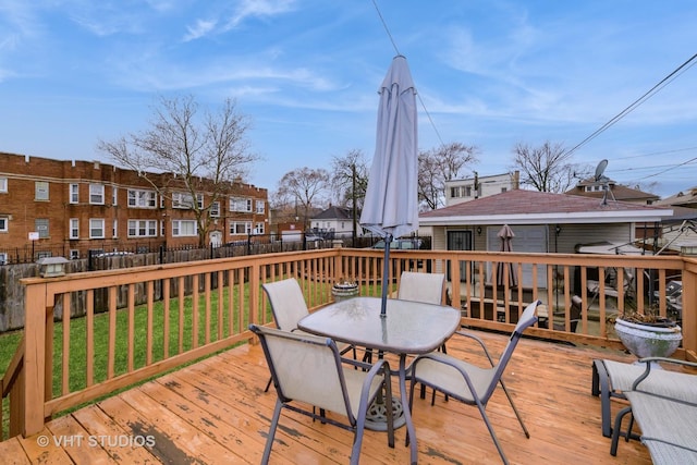 deck with a yard, outdoor dining space, fence, and a residential view
