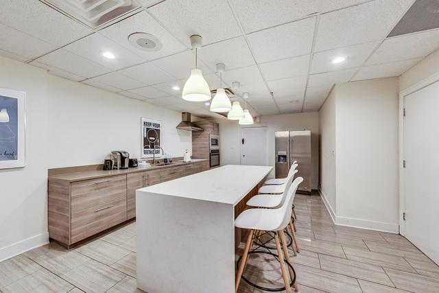 kitchen with a kitchen breakfast bar, black oven, a center island, wall chimney exhaust hood, and stainless steel fridge with ice dispenser