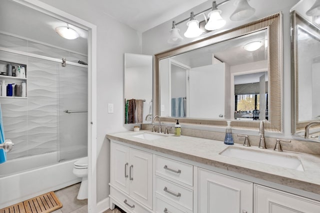 bathroom featuring tile patterned floors, toilet, double vanity, and a sink