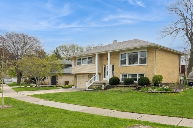 split foyer home with a front yard, a garage, brick siding, driveway, and a chimney