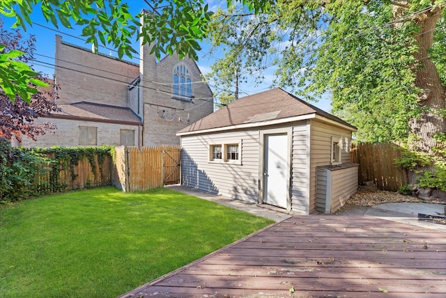 exterior space featuring a fenced backyard, a wooden deck, an outdoor structure, and a lawn