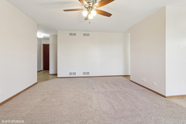 unfurnished room with light colored carpet, a ceiling fan, and baseboards